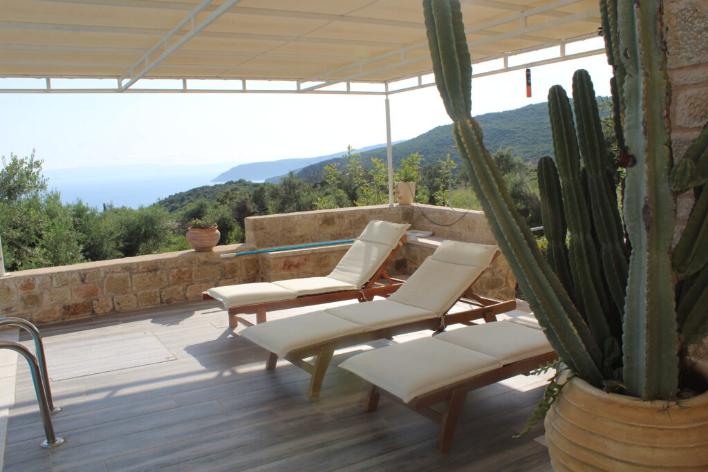 Mediterranean terrace at Villa Leonidas with sun loungers, shaded pergola, and ocean views in Kardamyli